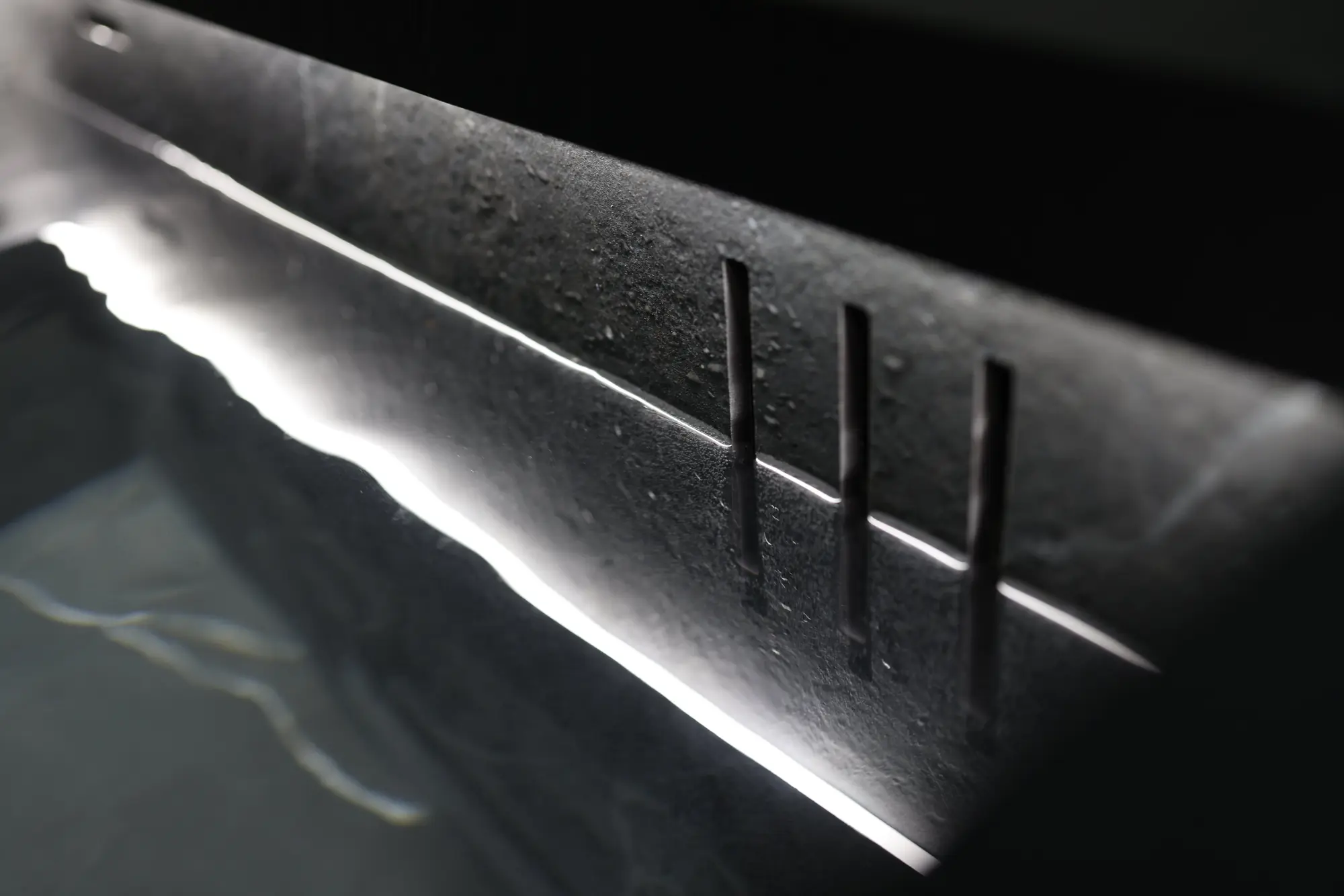 Light raking across the machined overflow slot of a stone cold plunge