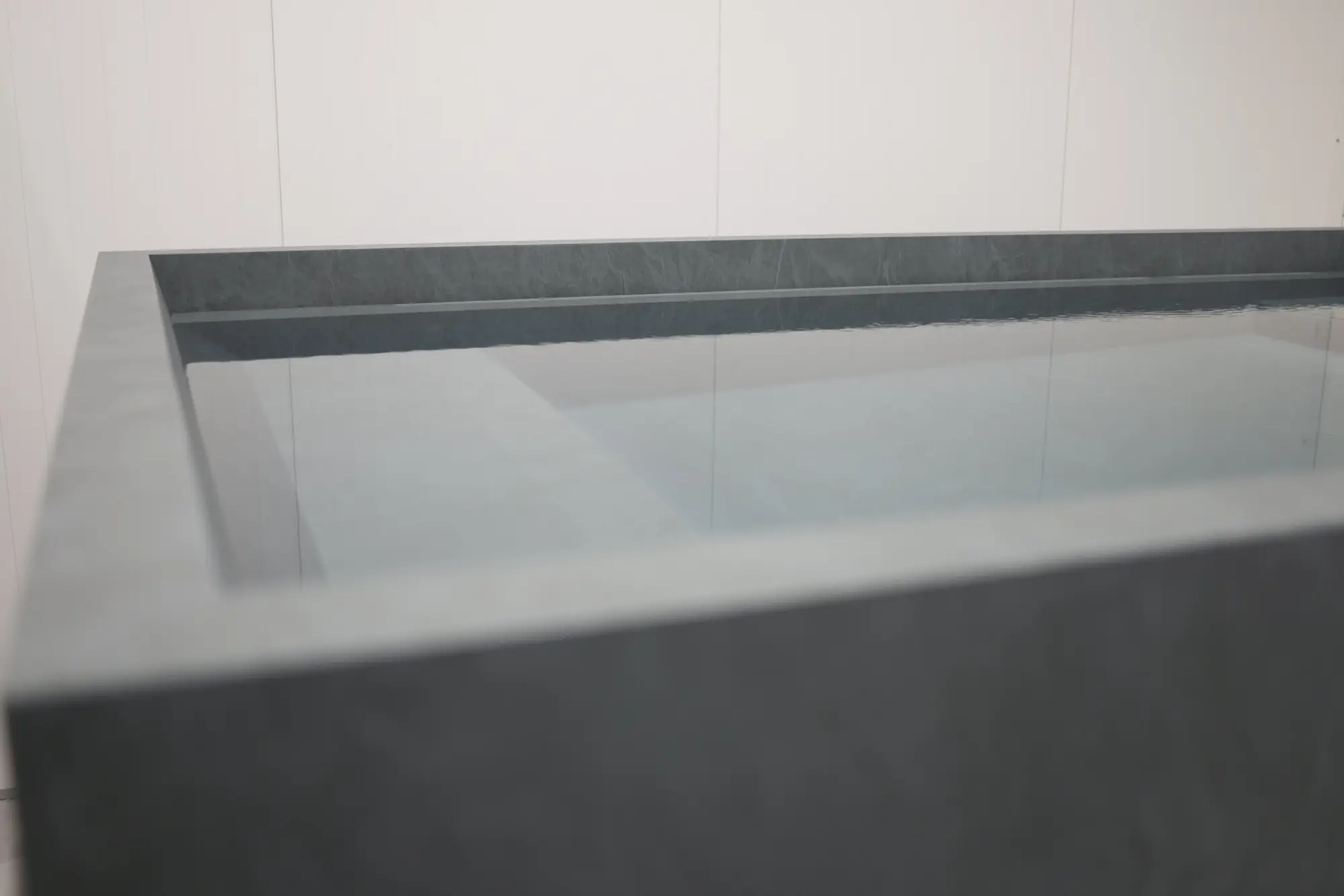 Finished corner of a stone cold plunge filled with still water
