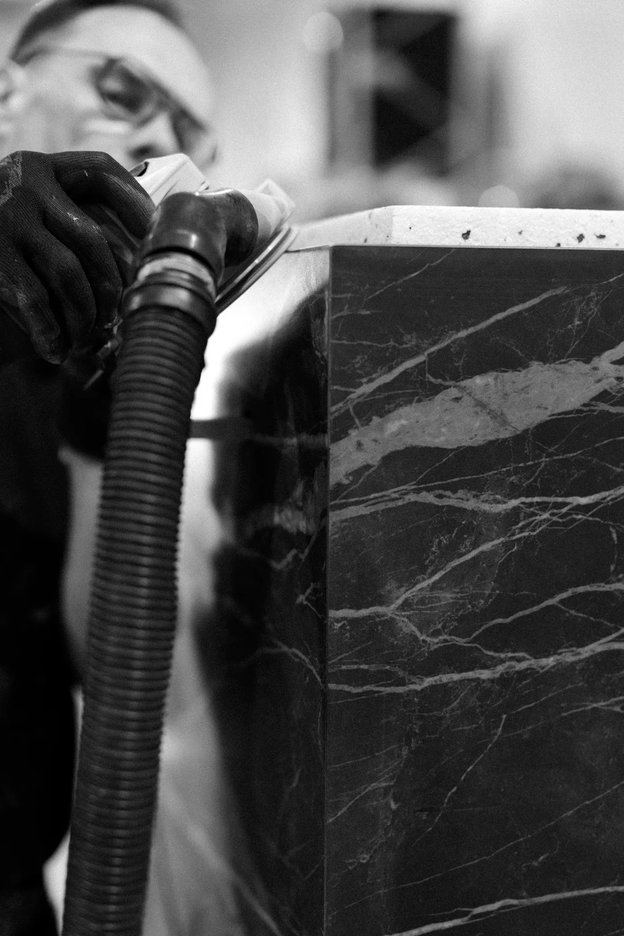 Craftsman sanding a dark stone cold plunge panel by hand in the Nordic Vitality workshop